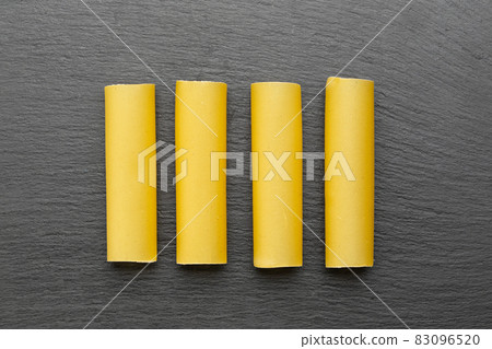 Raw dried cannelloni pasta, a tubular pasta that is usually stuffed with meat or vegetables 83096520