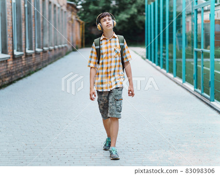 happy teen boy portrait on the way to school, he is listening to music on headphones, education and back to school concept 83098306