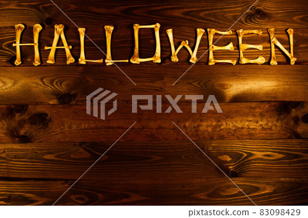 Lettering from the bones of the word Halloween on a beautiful dark brown wooden background. Design to celebrate Halloween day. Lettered design. Happy Halloween. Scary inscription. Copy space for text Lettering from the bones of the word Halloween on a beautiful dark brown wooden background. Design to celebrate Halloween day. Lettered design. Happy Halloween. Scary inscription. Copy space for text 83098429