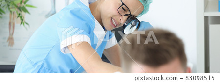 Woman doctor with glasses examining rash on skin of buttocks of young man in clinic 83098515