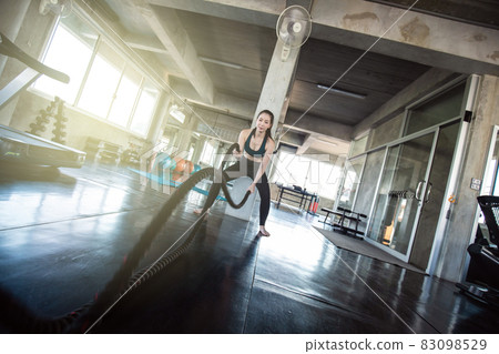 Muscular asian women exercise with rope in fitness gym 83098529