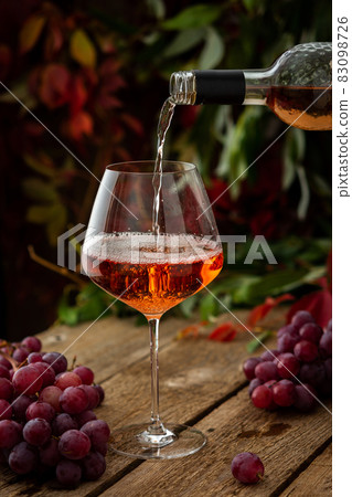 Wine is poured from the bottle into the glass Wine is poured from the bottle into the glass 83098726