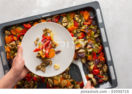 Woman lays stewed vegetables in a plate Woman lays stewed vegetables in a plate 83098728