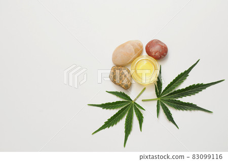 Marijuana leaves, cbd oil, sea stones, spa recreation. Fresh cannabis leaves close up, isolated on white background. 83099116
