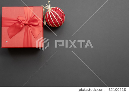 Gift red box with a bow and a handmade Christmas ball in the upper corner on a dark gray background. Christmas mockup. Top view 83100318