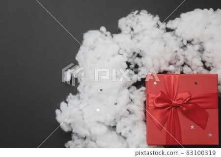 Red box with a bow and artificial fiberfil snow on a dark gray background. Christmas mockup. Top view Red box with a bow and artificial fiberfil snow on a dark gray background. Christmas mockup. Top view 83100319