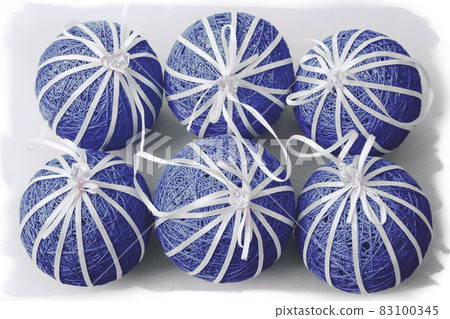 Red New Year's handmade balls are laid out around a white ball on the left on a light background with a white irregular frame. Festive postcard. Top view 83100345