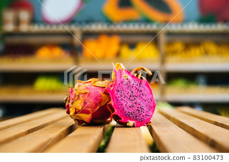 Close-up front view of fresh juicy pitahaya standing on wooden pallet at fruit and vegetables section of grocery store. Close-up front view of fresh juicy pitahaya standing on wooden pallet at fruit and vegetables section of grocery store. 83100473