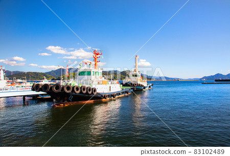 It is a harbor scenery where you can see the tugboat. Please in the background of the seascape. -1 83102489