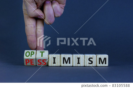 Pessimism or optimism symbol. Businessman turns cubes and changes the word 'pessimism' to 'optimism'. Beautiful grey table, grey background. Business, optimism or pessimism concept. Copy space. 83105588