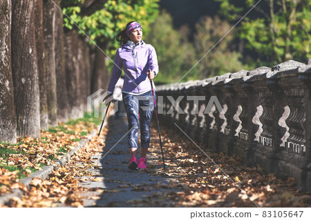 Nordic walking on sidewalk. A young woman practices_2 Nordic walking on sidewalk. A young woman practices_2 83105647