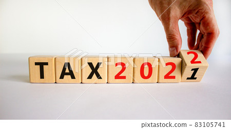 2022 tax new year symbol. Businessman turns wooden cubes and changes words 'Tax 2021' to 'Tax 2022'. Beautiful white background, copy space. Business, 2022 tax new year concept. 83105741