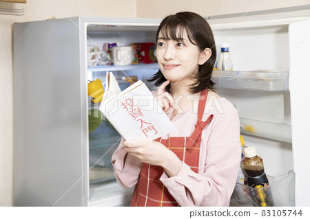 A woman thinking about investing with the refrigerator open A woman thinking about investing with the refrigerator open 83105744