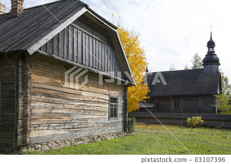 An old rustic wooden hut. In the background there is a rustic wooden church. An old rustic wooden hut. In the background there is a rustic wooden church. 83107396