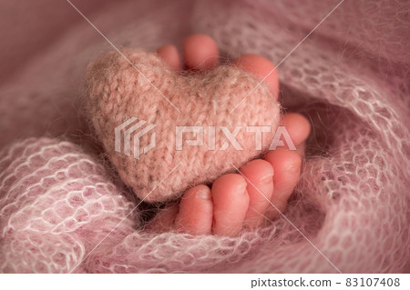 legs and toes of a newborn in a soft pink blanket with a heart 83107408