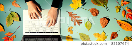 Autumn leaves with person using a laptop computer Autumn leaves with person using a laptop computer 83107674