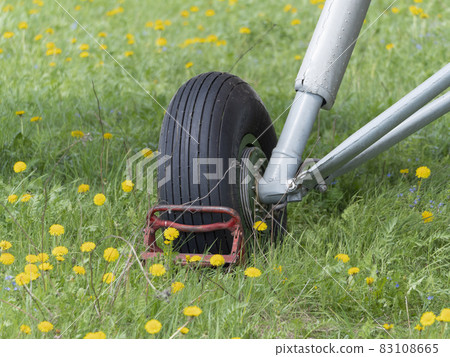 An-2 aircraft landing gear in the grass and yellow dandelions An-2 aircraft landing gear in the grass and yellow dandelions 83108665