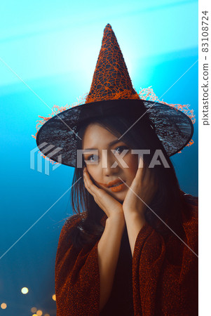 Portrait of beautiful young woman in witch halloween costume wear witches hat holding broom over spooky dark magic background - Halloween party art design. 83108724