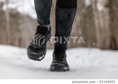Winter running shoes woman training cardio outdoors jogging on white snow in cold weather. Closeup of feet wearing fitness footwear Winter running shoes woman training cardio outdoors jogging on white snow in cold weather. Closeup of feet wearing fitness footwear 83108891