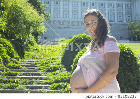 Pregnant woman with pink dress in a park Pregnant woman with pink dress in a park 83109238
