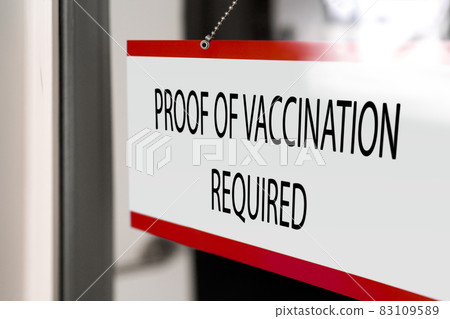 Proof of vaccination required to enter non essential business hanging at window store. Banner of coronavirus vaccine requirement for entering indoors Proof of vaccination required to enter non essential business hanging at window store. Banner of coronavirus vaccine requirement for entering indoors 83109589