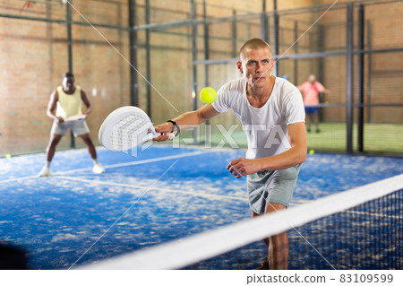 Focused man playing paddle ball match on closed court Focused man playing paddle ball match on closed court 83109599
