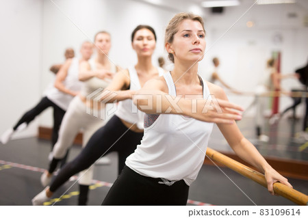 Ballet dancers practicing at barre in dance class 83109614