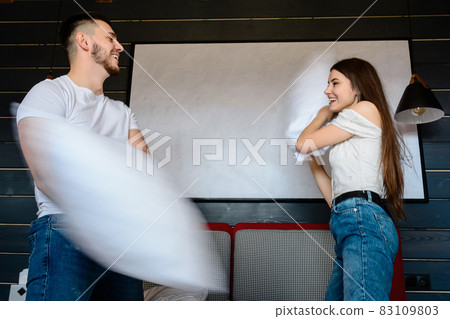 Pillow fight in a hotel room, rest of a young couple, advertising of hotel rooms. Pillow fight in a hotel room, rest of a young couple, advertising of hotel rooms. 83109803