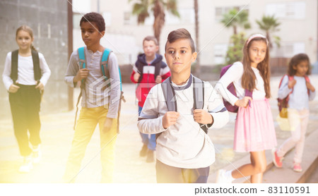 Positive boy standing near school, children on background Positive boy standing near school, children on background 83110591