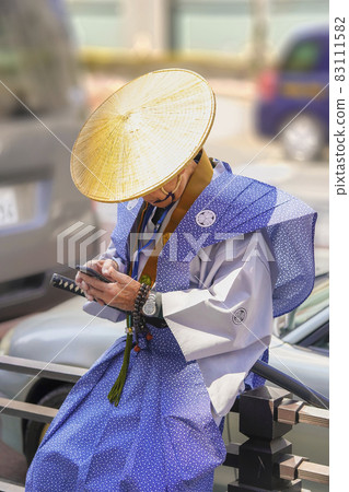 [Minato-ku, Tokyo] An elderly person playing with a smartphone in the form of a samurai during the procession of the Zojoji memorial service. 83111582
