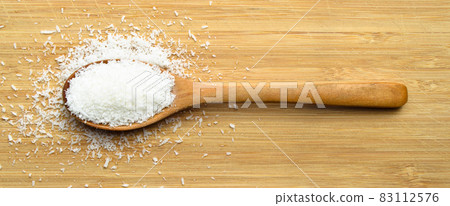 Ground fresh coconut in wooden spoon on bamboo cutting board 83112576