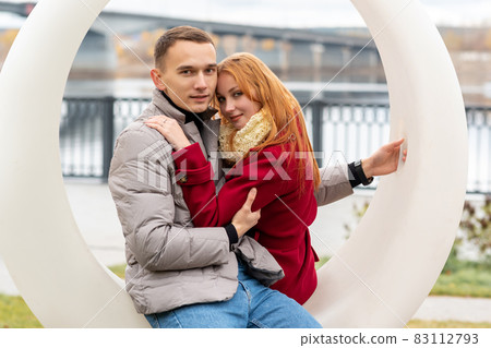 young couple in the autumn park sitting on a swing 83112793