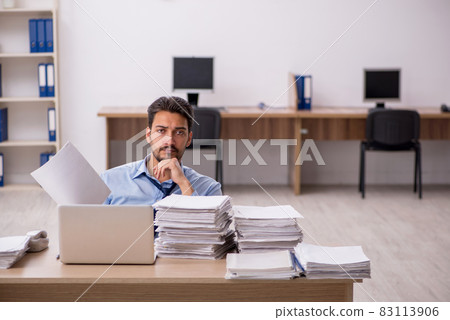 Young male employee and too much work in the office Young male employee and too much work in the office 83113906