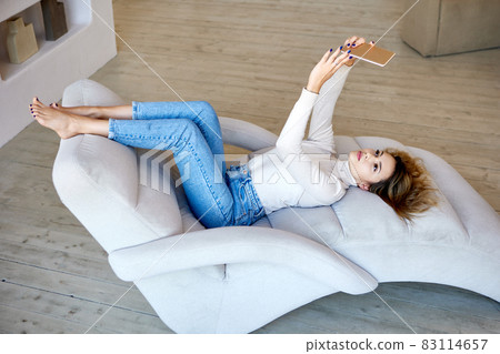 Woman is making selfie by phone while lies on comfort sofa. Woman is making selfie by phone while lies on comfort sofa. 83114657