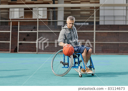 Man with disability playing basketball outdoors 83114673