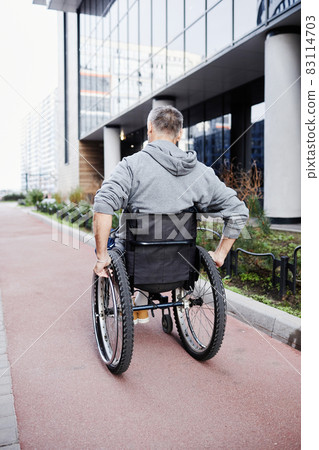 Patient in wheelchair walking outdoors Patient in wheelchair walking outdoors 83114703