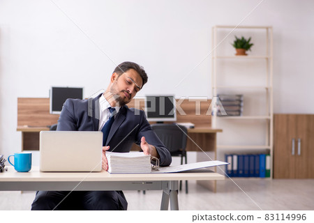Young male employee sitting at workplace Young male employee sitting at workplace 83114996