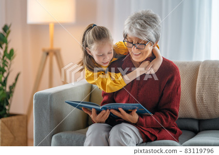 Grandmother reading a book to granddaughter. Grandmother reading a book to granddaughter. 83119796