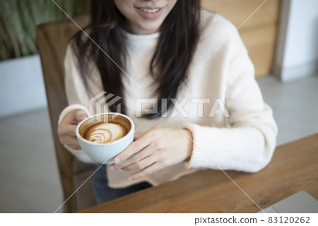 Smiling woman in sweater holding cup of coffee. Smiling woman in sweater holding cup of coffee. 83120262