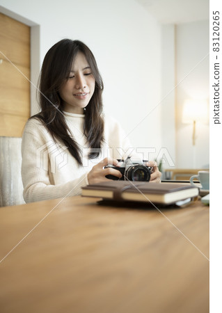 Young female photographer holding camera while sitting in her office room. Young female photographer holding camera while sitting in her office room. 83120265