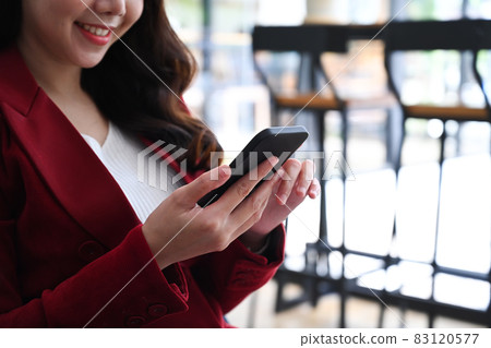 Smiling businesswoman sitting in office and using smart phone. Smiling businesswoman sitting in office and using smart phone. 83120577