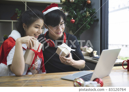Happy asian couple holding gift box and having video call on laptop computer. Happy asian couple holding gift box and having video call on laptop computer. 83120764