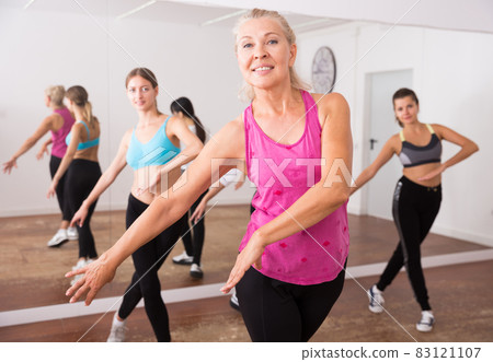 Group of active smiling people dancing together in dance studio 83121107