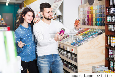 happy couple examining various paints in paint store 83121128
