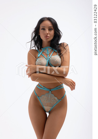 Hot sexy woman in blue lace lingerie looking at camera touching body 83122429