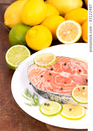 Steak of red fish and sliced lemons on wooden table Steak of red fish and sliced lemons on wooden table 83122497