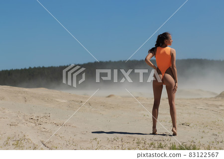 Fit woman in swimwear walking on sandy beach 83122567