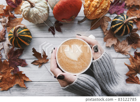 Female hands holding a cup of hot coffee, autumn flat lay 83122785