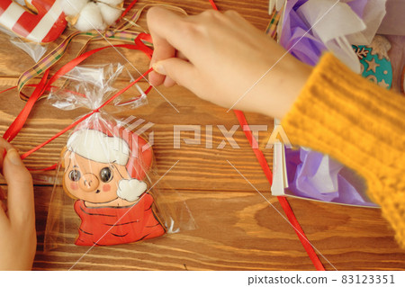 Women's hands pack gingerbread in form of pig. 83123351