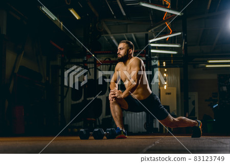Full-length portrait of young sportive man doing stretching. Gym training 83123749